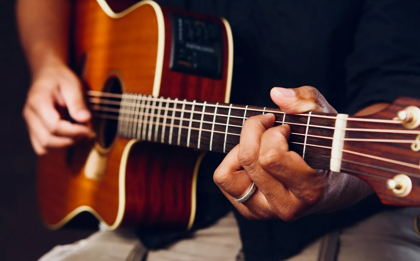 Hands playing an acoustic guitar